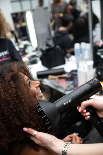 Professional stylists preparing a model&rsquo;s hair backstage using UNITE products at London Fashion Week with Sally Beauty.
