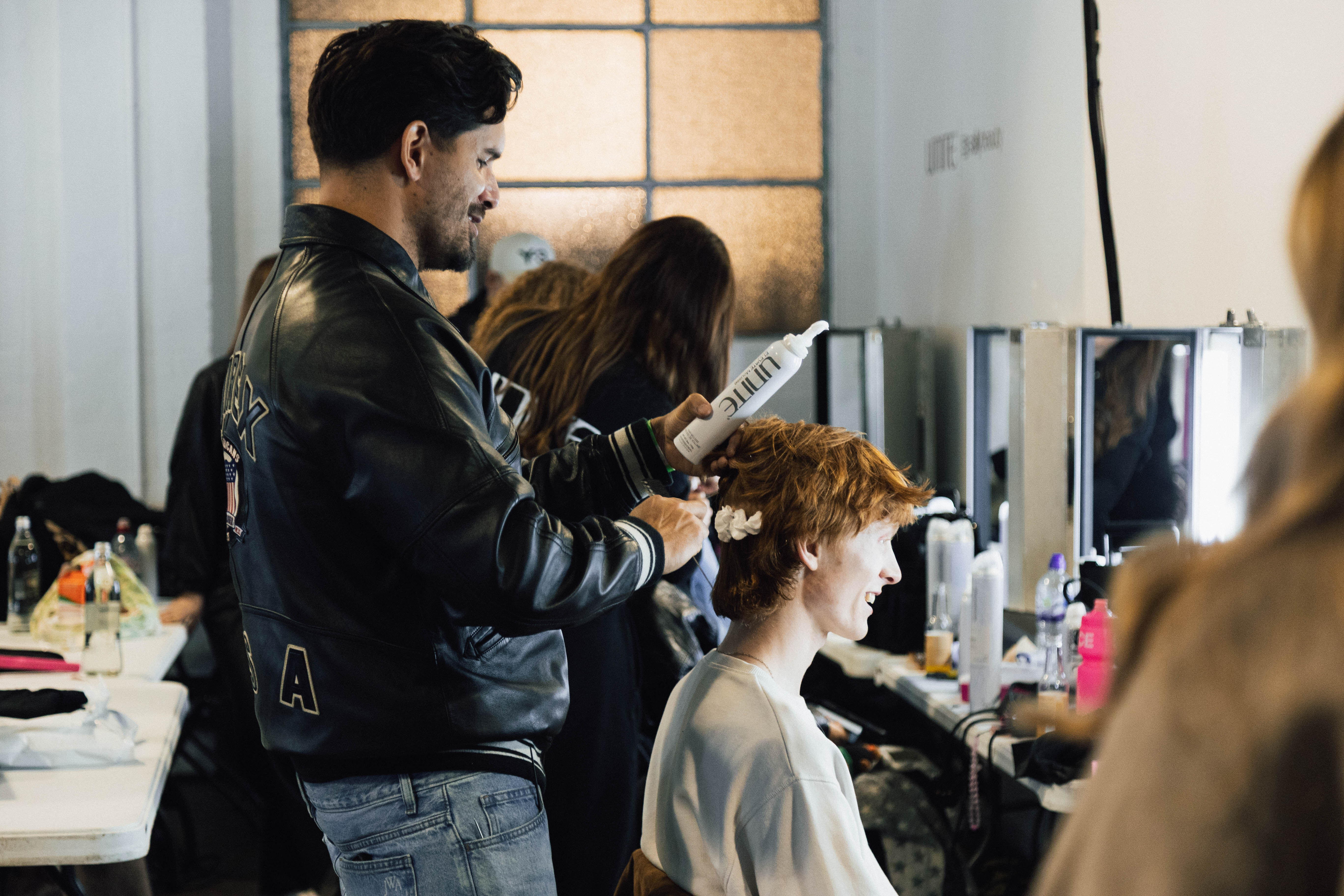 Backstage hairstylist using UNITE styling products to create runway hair looks at London Fashion Week with Sally Beauty.