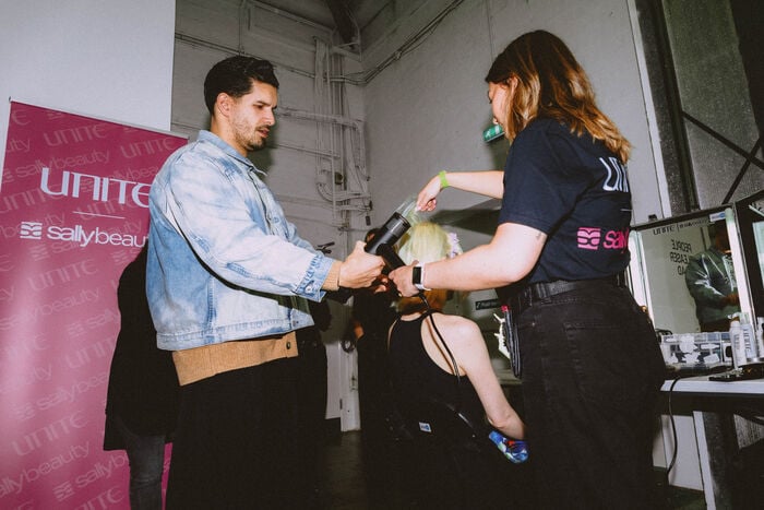 Backstage hairstylist using UNITE styling products to create runway hair looks at London Fashion Week with Sally Beauty.