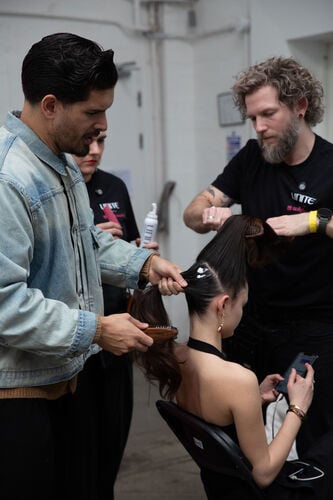 Backstage stylists creating sleek runway hair using professional tools and UNITE products with Sally Beauty.
